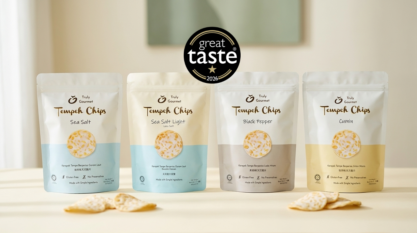 Four packs of Truly Gourmet Tempeh Chips — Sea Salt, Sea Salt Light, Black Pepper and Cumin — arranged on a warm ivory background beside the Great Taste 2026 one-star award roundel.